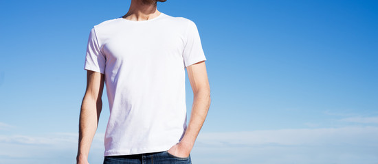 Photo of a man wearing white t-shirt. Blue sky on background