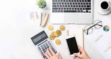 A woman is calculating the fee, profit and doing a payment online on a modern marble office table, mock up, top view, copy space, flat lay, lifestyle