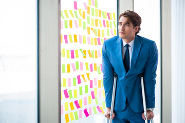 Young handsome man with crutches in conflicting priorities conce