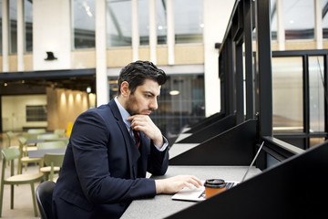 Saudi Arabian businessman in an airport business lounge using a laptop