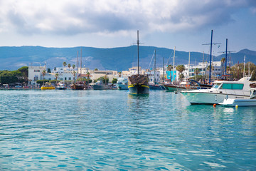 Kos harbor on bright summer day, Greece. Beautiful clouds and turquoise waters of Mediterranean sea. Ships and boats stay in bay. 