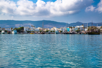Naklejka premium Kos harbor on bright summer day, Greece. Beautiful clouds and turquoise waters of Mediterranean sea. Ships and boats stay in bay. 