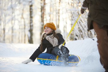 Full length portrait of happy little girl enjoying sleigh ride in beautiful winter forest, copy space