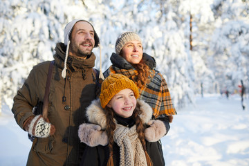 Portrait of happy family in beautiful winter forest  posing together looking away, copy space