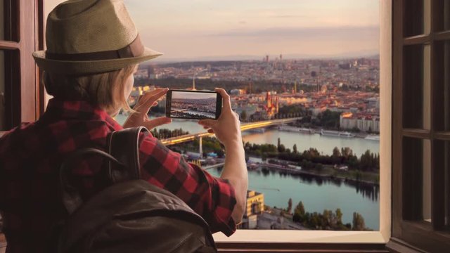 tourist taking picture of vienna skyline at sunset,woman takes photo of city from high pov using smartphone