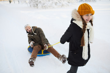 Fototapeta na wymiar Portrait of happy family enjoying sleigh ride in winter forest lit by sunlight, copy space
