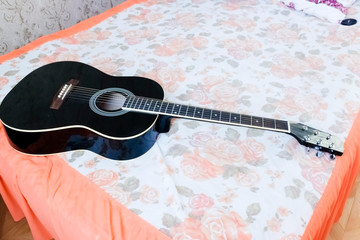 Acoustic guitar laying on bed low angle shot from bottom with plectrum on the body