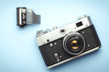 Vintage old film camera and a 35mm reel of film on a blue background, top view