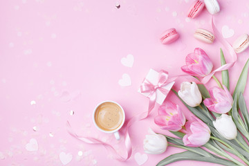 Morning cup of coffee, cake macaron, gift box and spring tulip flowers on pink background. Beautiful breakfast for Women day, Mother day. Flat lay.