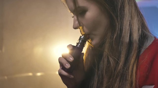 Hot girl with red lips vaping and looking at camera