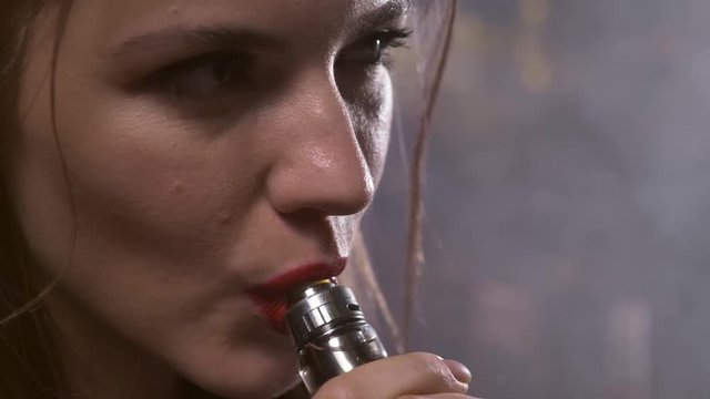 Close up shot of a young  hot girl elegantly vaping through her nose and mouth