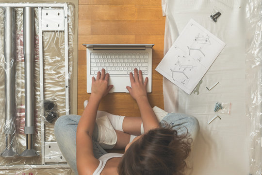 Female with laptop and furniture assembling Instruction. Top view