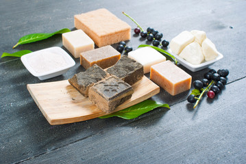 cosmetic clay, soaps, henna blocks, raw shea butter on black wood table