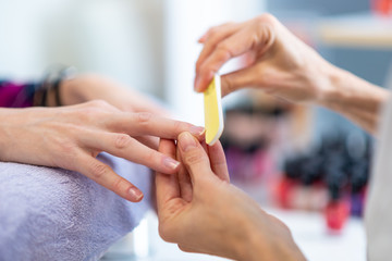 Obraz na płótnie Canvas Closeup of manicurist filing finger nails
