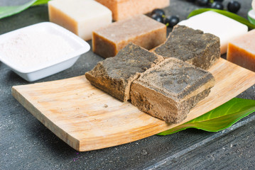 cosmetic clay, soaps, henna blocks, raw shea butter on black wood table