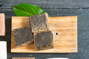 cosmetic clay, soaps, henna blocks, raw shea butter on black wood table