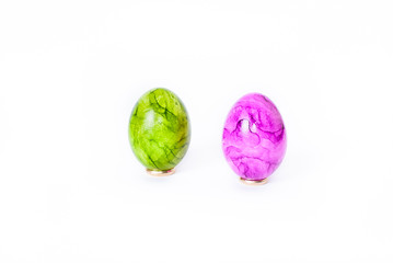 Two painted easter eggs (green and purple) standing on white background