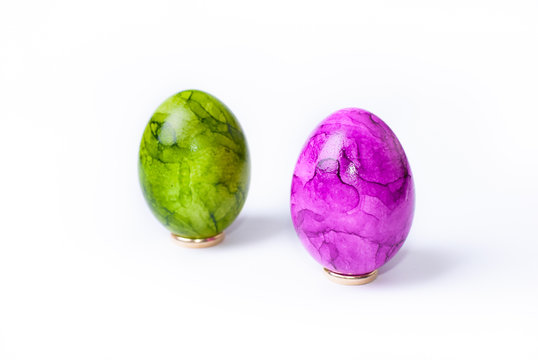 Two painted easter eggs (green and purple) standing on white background