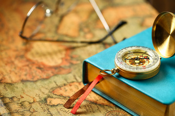 close up view of Compass and book on vintage old map background