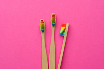 Image of three toothbrushes with rainbow-colored bristles.