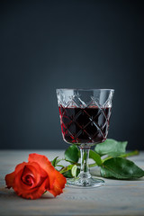 glass of red wine and rose a on a wood background