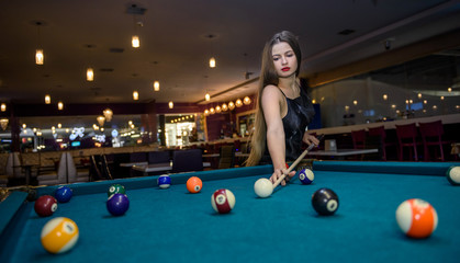 Young and beautiful woman in pub playing billiard