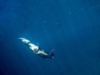 Woman swimming underwater on a blue sea and clear water with good visibility for snorkeling.