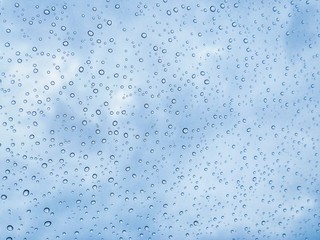 Rain drops on window glasses surface with cloudy background . Natural Pattern of raindrops isolated on cloudy background. 