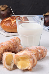 glass of milk with sugary croissants and sweet rolls on white textured background