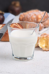 glass of milk with sugary croissants and sweet rolls on white textured background