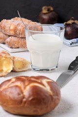 glass of milk with sugary croissants and sweet rolls on white textured background