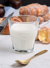 glass of milk with sugary croissants and sweet rolls on white textured background