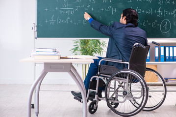Young handsome man in wheelchair in front of chalkboard 