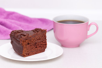 Delicious chocolate cake on plate with pink cup of coffee on table on light background