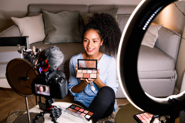 Female vlogger showing cosmetic accessories while recording content