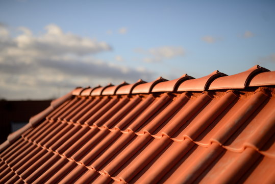 D&auml;cher vom Dachdecker mit roten Dachziegeln. Pfannen auf Stadt Haus Neubau mit Abendrot Himmel im Hintergrund.