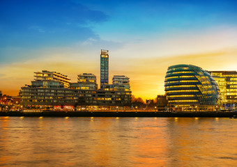 Cityscape and skyline of London in sunset light reflected on the Thames river at dusk to down