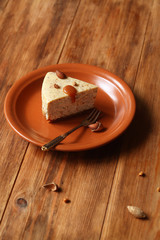 Piece of Almond Cheesecake  with salted caramel, on brown plate, on wooden table.