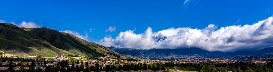 Aerial, done view of white clouds over Mount San Gorgonio in the San Bernardino Mountains and blue sky above Yucaipa, California after a rain storm
