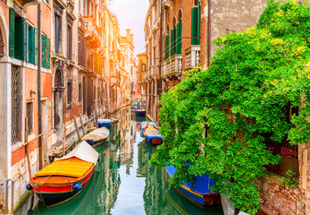 Obraz na płótnie Canvas Narrow canal with boat and bridge in Venice, Italy. Architecture and landmark of Venice. Cozy cityscape of Venice.