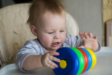 happy toddler baby boy sorting colorful rings on pyramid