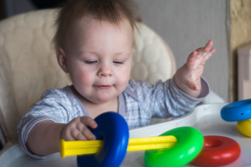 happy toddler baby boy sorting colorful rings on pyramid