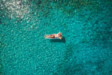 aerial view of a beautiful young woman in bikini on a matress in the sea