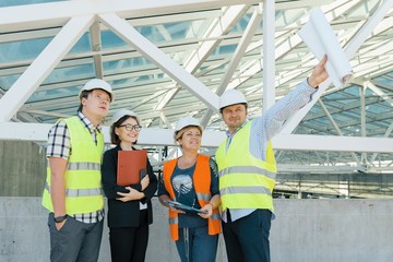Obraz premium Team of builders engineer architect on the roof of construction site. Building, development, teamwork and people concept