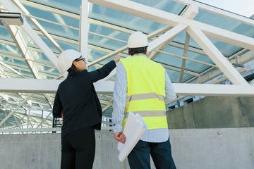 Woman architect and man builder at construction site, back view. Building, development, teamwork and people concept