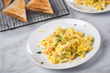 Räucherlachs Rührei mit Dill und Vollkorn Toast auf Marmor Hintergrund