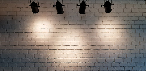 Hanging spotlight illuminate at white brick wall background with copy space - obrazy, fototapety, plakaty