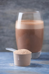 Scoop of Whey Protein and a Glass of Chocolate Protein Shake with milk and banana. Sport nutrition. Wooden background. Copy space. 