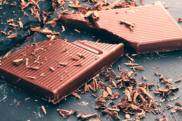 Broken dark chocolate and chocolate flakes on a wooden table