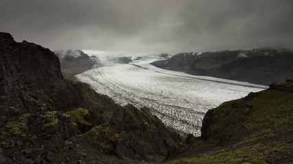 Skaftafellsjokull glacier tongue and volcanic mountains around with overcast sky above from a hiking trail in Skaftafell National Park, Southern Iceland.